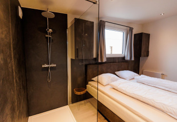 Camera lodge moderna con doccia, letto matrimoniale e finestra, Beachlodge Deluxe ǀ to, Vakantiepark Leukermeer, Paesi Bassi.