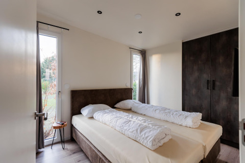 Moderne slaapkamer in Beachlodge Deluxe ǀ to bij Vakantiepark Leukermeer, Nederland, met groot tweepersoonsbed
