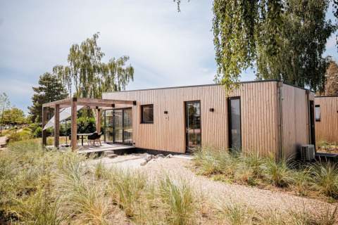 Modern Beachlodge Deluxe at Vakantiepark Leukermeer, Netherlands, with wooden terrace and greenery.