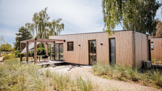 Moderne Beachlodge Deluxe bij Vakantiepark Leukermeer, Nederland, met houten terras en groen.