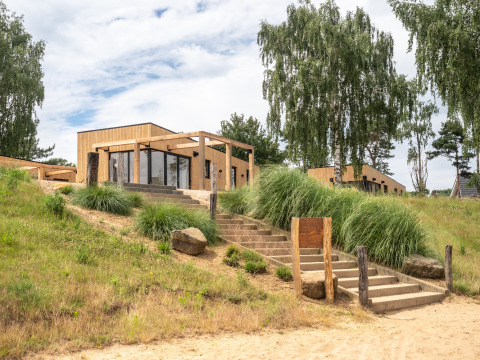 Buitenzicht op Beachlodge Deluxe in Vakantiepark Leukermeer, houten huisjes en groene natuur.