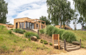 Exterior of Beachlodge Deluxe at Vakantiepark Leukermeer, wooden cabins, steps and lush greenery.