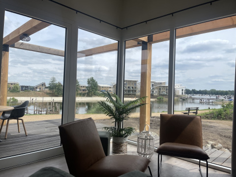 Vue depuis Beachlodge Deluxe à Vakantiepark Leukermeer, Pays-Bas, montrant lac, terrasse et lodges modernes.
