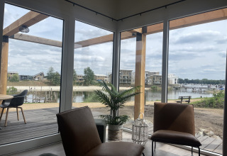 View from Beachlodge Deluxe at Vakantiepark Leukermeer, Netherlands, showing lake, patio, and modern lodges.