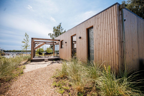 Beachlodge Deluxe im Vakantiepark Leukermeer, Niederlande: moderne Holzlodge mit Terrasse am Wasser.