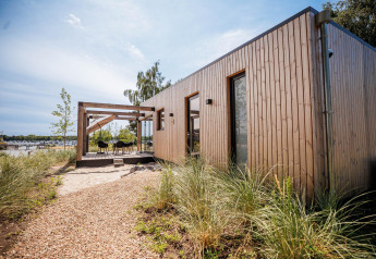 Beachlodge Deluxe aan Vakantiepark Leukermeer, Nederland: moderne houten lodge met terras bij het water.