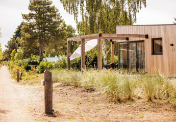 Buitenaanzicht van Beachlodge Deluxe op Vakantiepark Leukermeer in Nederland met houten terras en groen.
