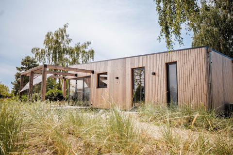 Moderne Beachlodge Deluxe in Vakantiepark Leukermeer, Nederland, omgeven door natuur en bomen.