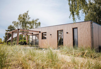 Moderne Beachlodge Deluxe ved Vakantiepark Leukermeer i Holland, omgivet af grøn natur og træer.