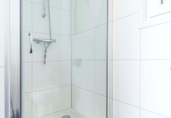 Moderne Dusche im weiß gefliesten Badezimmer der Velthorst-Hütte, EuroParcs Parc du Soleil, Niederlande.