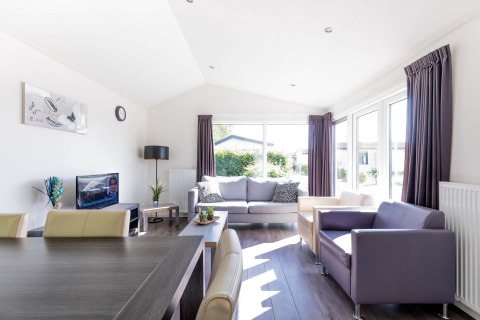 Heldere, moderne woonkamer in de Velthorst-cabine bij EuroParcs Parc du Soleil in Nederland met grote ramen.