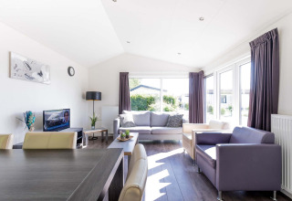 Heldere, moderne woonkamer in de Velthorst-cabine bij EuroParcs Parc du Soleil in Nederland met grote ramen.
