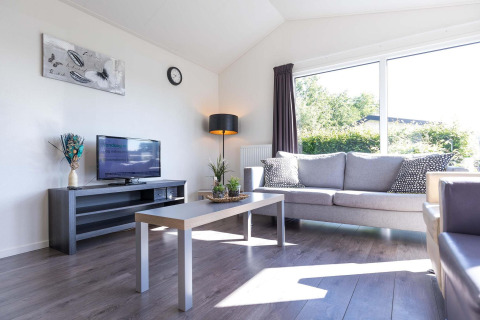 Helles Wohnzimmer in einer Velthorst-Hütte im EuroParcs Parc du Soleil, Niederlande, mit Sofa und Fenster.