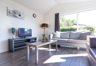 Séjour lumineux dans un chalet Velthorst à EuroParcs Parc du Soleil, Pays-Bas, avec canapé et grande fenêtre.