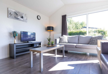 Helles Wohnzimmer in einer Velthorst-Hütte im EuroParcs Parc du Soleil, Niederlande, mit Sofa und Fenster.