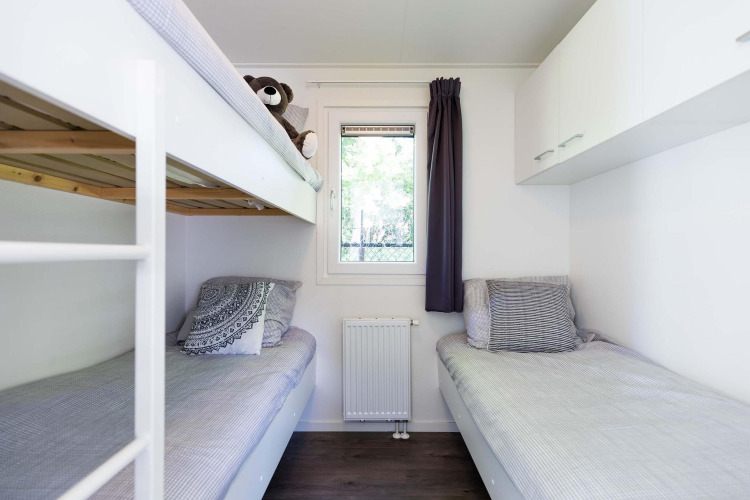 Dormitorio luminoso y moderno con litera y cama individual en una cabaña Velthorst de EuroParcs Parc du Soleil.