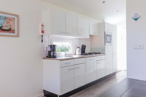 Cocina moderna en una cabaña Velthorst en EuroParcs Parc du Soleil, Países Bajos, con gabinetes blancos.