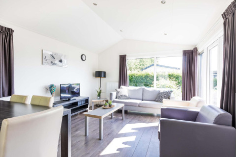 Modernes Wohnzimmer in der Velthorst-Hütte im EuroParcs Parc du Soleil in den Niederlanden mit großen Fenstern.