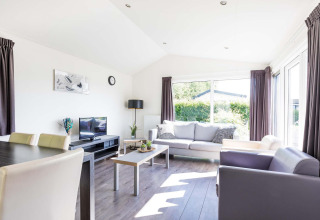Moderne woonkamer in de Velthorst cabin in EuroParcs Parc du Soleil, Nederland, met licht en comfortabele zetels.