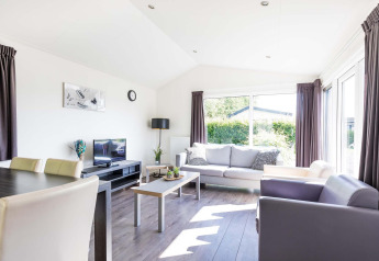 Modernes Wohnzimmer in der Velthorst-Hütte im EuroParcs Parc du Soleil in den Niederlanden mit großen Fenstern.