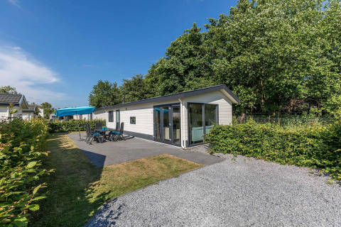 Außenansicht der Velthorst-Hütte im EuroParcs Parc du Soleil, Niederlande, mit Terrasse und Gartenmöbeln.
