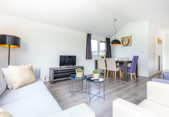 Lichte, moderne woonkamer in een Velthorst-cabine bij EuroParcs Parc du Soleil met eettafel.