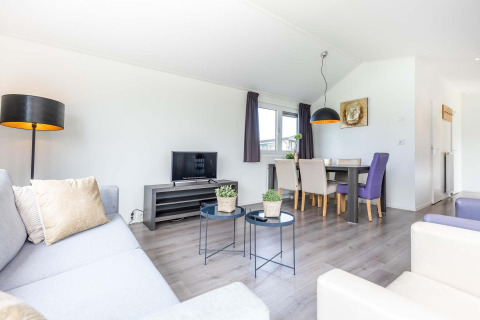 Lichte, moderne woonkamer in een Velthorst-cabine bij EuroParcs Parc du Soleil met eettafel.