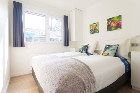 Helles Schlafzimmer in einer Velthorst-Hütte im EuroParcs Parc du Soleil, Niederlande, mit zwei Betten.