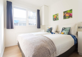 Helles Schlafzimmer in einer Velthorst-Hütte im EuroParcs Parc du Soleil, Niederlande, mit zwei Betten.