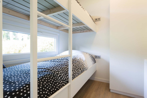 Moderne stapelbedden in een lichte kamer met groot raam in de Velthorst-hut, EuroParcs Parc du Soleil, Nederland.
