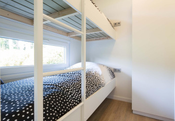Modern stapelbed in een lichte kamer met groot raam in de Velthorst-cabine, EuroParcs Parc du Soleil.