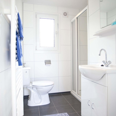 Salle de bain moderne et lumineuse dans une cabane Velthorst à EuroParcs Parc du Soleil aux Pays-Bas, avec douche.