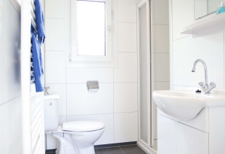 Salle de bain moderne et lumineuse dans une cabane Velthorst à EuroParcs Parc du Soleil aux Pays-Bas, avec douche.