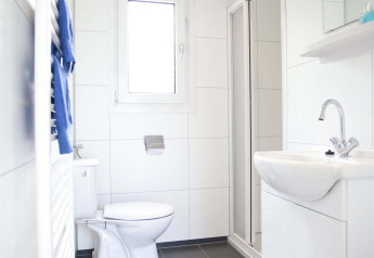 Salle de bain moderne et lumineuse dans une cabane Velthorst à EuroParcs Parc du Soleil aux Pays-Bas, avec douche.
