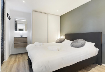 Camera moderna per glamping con letto matrimoniale, lavandino, specchio e pavimento in legno.