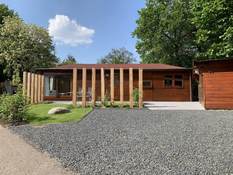 Modern houten Tiny Chalet in Bungalowpark Het Verscholen Dorp met tuin en grindpad, Nederland.