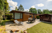 Vue extérieure du Tiny Chalet au Bungalowpark Het Verscholen Dorp, Pays-Bas, avec terrasse et chaises.