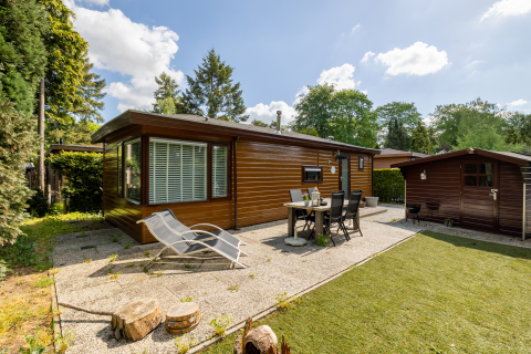Vue extérieure du Tiny Chalet au Bungalowpark Het Verscholen Dorp, Pays-Bas, avec terrasse et chaises.