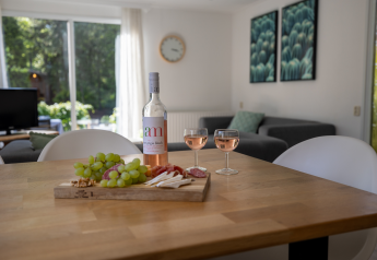 Mesa en Tiny Chalet, Het Verscholen Dorp, Países Bajos, con vino rosado, dos copas y tabla de quesos.