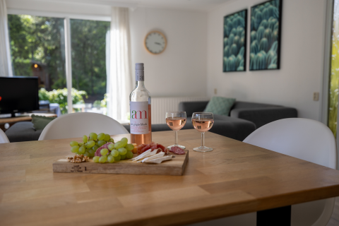 Tisch im Tiny Chalet, Het Verscholen Dorp, Niederlande, mit Wein, zwei Gläsern und Käseplatte.