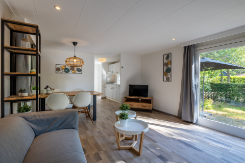 Sala moderna en el Tiny Chalet de Bungalowpark Het Verscholen Dorp, con decoración luminosa y vista al jardín.