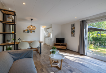 Moderne woonkamer in Tiny Chalet op Bungalowpark Het Verscholen Dorp met licht interieur en tuinzicht.