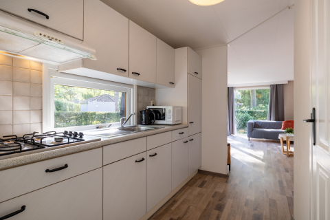 Lichte keuken in Tiny Chalet op Bungalowpark Het Verscholen Dorp met zicht op de woonkamer en tuin buiten.