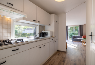 Bright kitchen inside Tiny Chalet at Bungalowpark Het Verscholen Dorp, view into living area and garden outside.