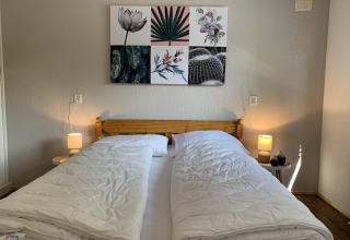 Slaapkamer in Tiny Chalet van Bungalowpark Het Verscholen Dorp, Nederland, met tweepersoonsbed en kunstwerk.