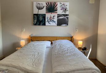 Bedroom inside Tiny Chalet at Bungalowpark Het Verscholen Dorp, Netherlands, with a double bed and wall art.
