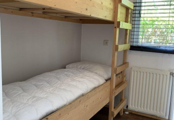 Letto a castello in legno con biancheria bianca in una piccola stanza al Tiny Chalet, Bungalowpark Het Verscholen Dorp, Paesi Bassi.