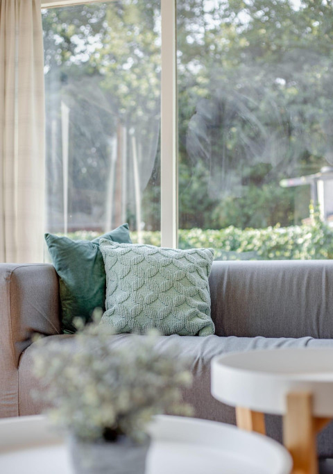 Salon lumineux du Tiny Chalet à Bungalowpark Het Verscholen Dorp, Pays-Bas, avec coussins verts.