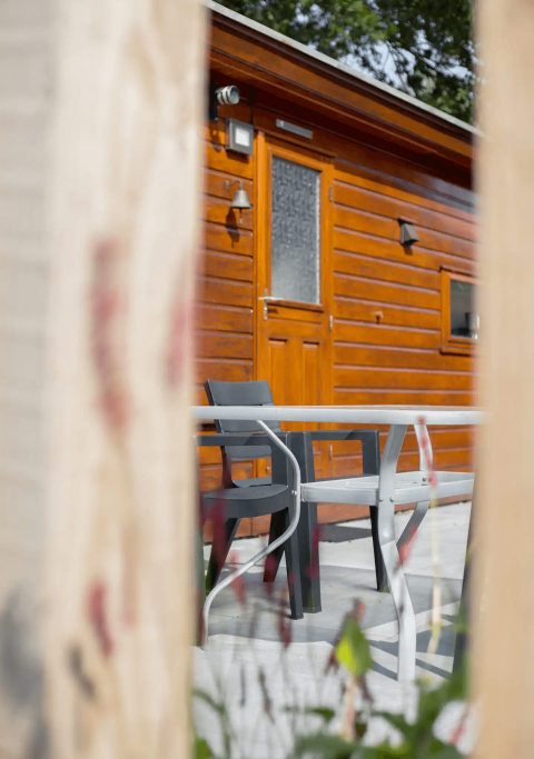 Vue d'une terrasse avec table et chaises devant un chalet au Tiny Chalet, Bungalowpark Het Verscholen Dorp.