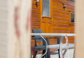 Blik op tafel en stoelen bij houten chalet van Tiny Chalet in Bungalowpark Het Verscholen Dorp in Nederland.